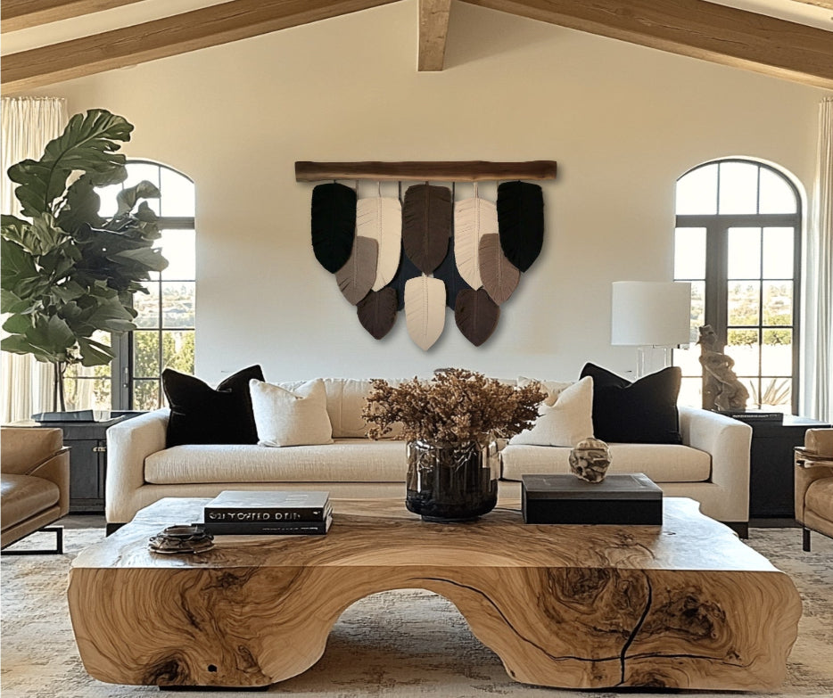 A wall hanging decor featuring macramé leaves on a walnut wood plank, displayed on a wall above a beige sofa in a well-lit living room.