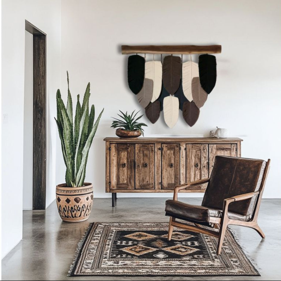 A wall hanging decor featuring a series of handcrafted macramé leaves in shades of beige, brown, and black, strung together on a wooden plank.